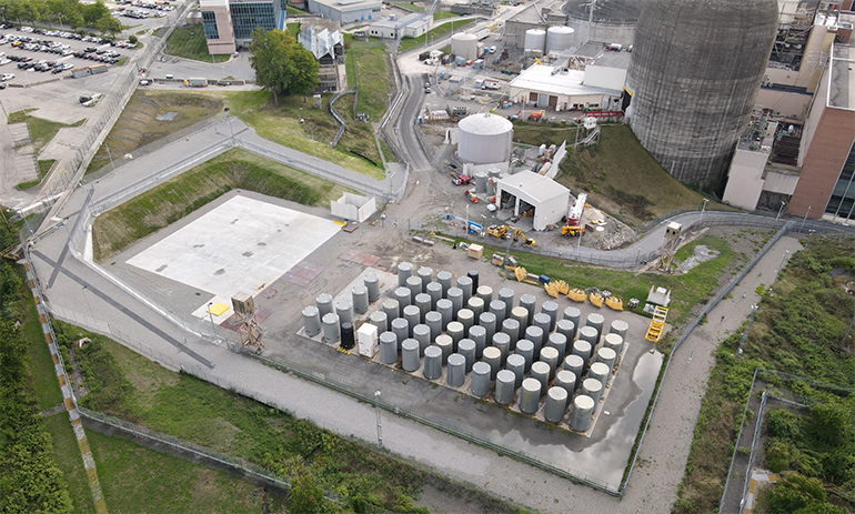 [ An off-site storage facility for spent nuclear fuel at U.S. nuclear company Holtec International; the cylinders, spaced at regular intervals from center to right in the photo, are casks ]